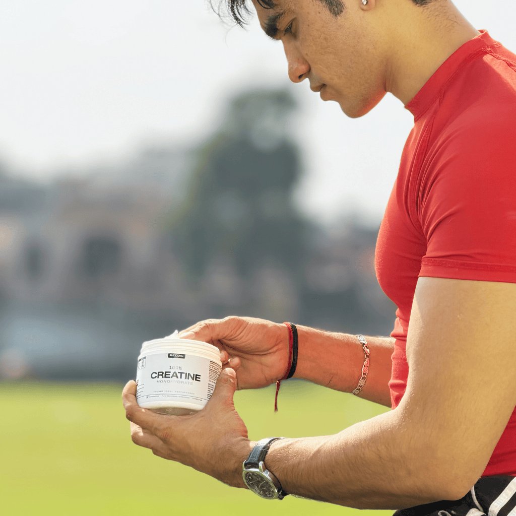 Person holding a container labeled 'CREATINE' outdoors